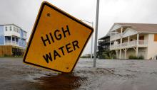 Flooded street with sign that says "high water"